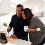 Couple cut vegetables together in a bright kitchen.